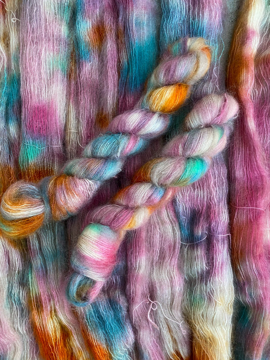 A skein of multicolored kid mohair yarn in a flace weight, featuring colors rose, blue, green, and orange