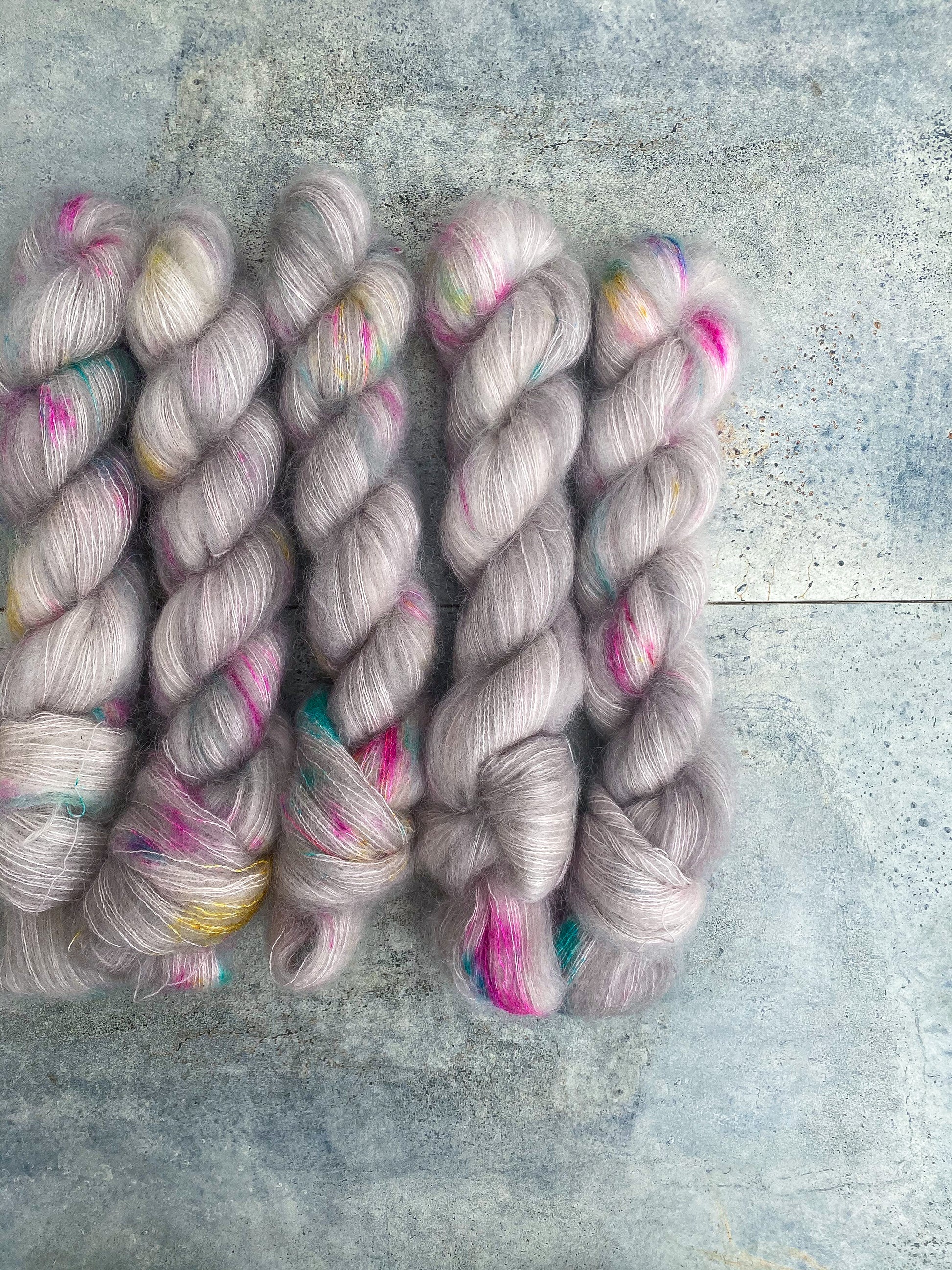 variegated grey yarn with pink, blue and yellow speckles shown on kid mohair lace weight yarn.