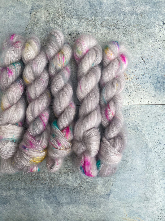 variegated grey yarn with pink, blue and yellow speckles shown on kid mohair lace weight yarn.